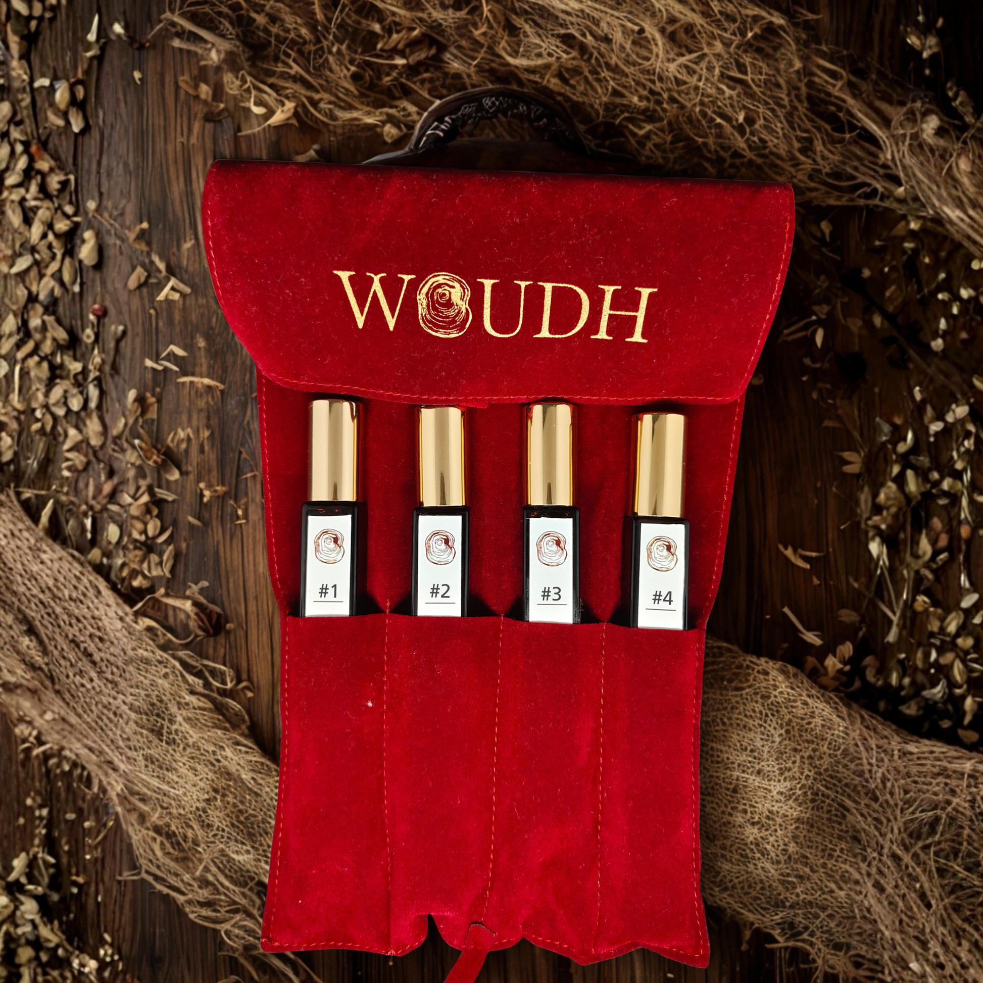 Set of cylindrical glass perfume bottles in a red velvet holder with 'WOUDH' branding on a rustic background.